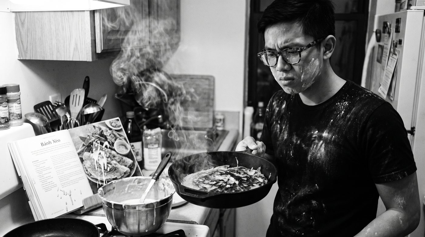 Minh Trần in a small apartment kitchen, cooking at the stove, the place warm with steam.